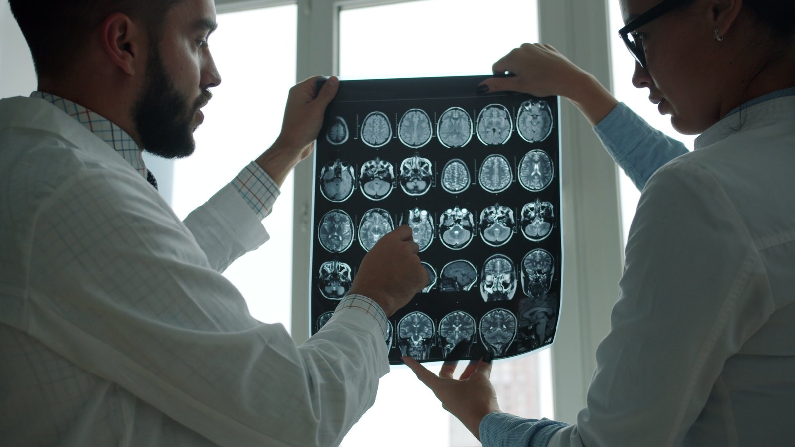 שני רופאים בוחנים יחד צילום MRI מול חלון מואר